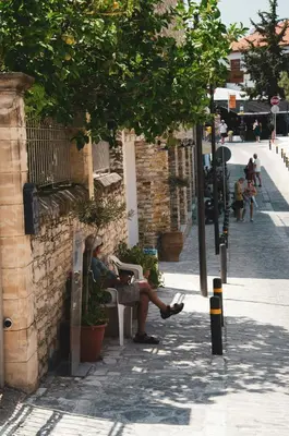 a woman sitting on a bench on a city street at Kallistheni - Stylish Studio Apartments in Lefkara in Pano Lefkara