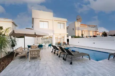 a patio with chairs and a pool and a house at Dahlia Napa Villa in Ayia Napa