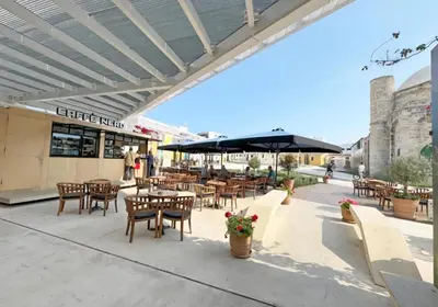 an outdoor patio with tables and chairs and an umbrella at Domus ArsEleAndra Studio-162 in Larnaka