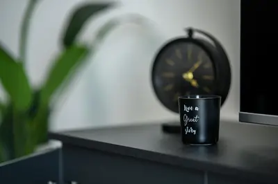 a black coffee cup sitting on a table next to a clock at Sunny 1-Bedroom Apartment - StaysbyDais in Larnaka