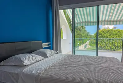 a bedroom with a bed with a blue wall and a window at Zima Cove Calm Coastal Oasis in Limassol