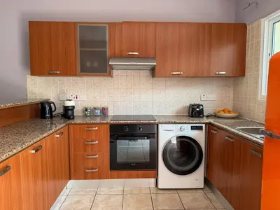 a kitchen with wooden cabinets and a washer at Zima Cove Calm Coastal Oasis in Limassol