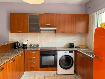 a kitchen with wooden cabinets and a washing machine at Zima Cove Calm Coastal Oasis in Limassol