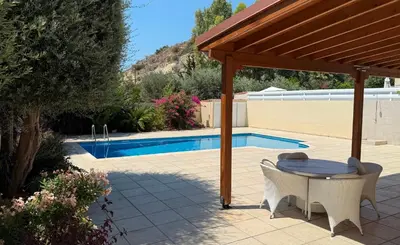 a patio with a table and chairs next to a pool at Villa Rossa in Pissouri