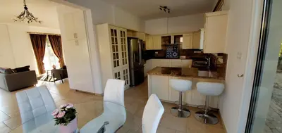 a kitchen with a glass table and white chairs at Villa Rossa in Pissouri