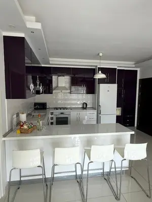 a kitchen with a counter with white chairs in it at Nicosia's Diamond in Nicosia
