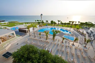 an aerial view of a resort with a pool and the ocean at Pernera Beach Hotel in Protaras