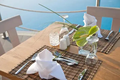a wooden table with a table cloth with a vase of flowers at Pernera Beach Hotel in Protaras