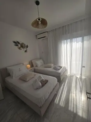 two beds in a white room with a window at Lazuli Skyline & Sea View Penthouse in Larnaka