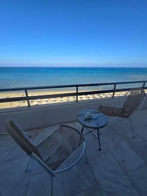 two chairs and a table on a balcony with the beach at Lazuli Skyline & Sea View Penthouse in Larnaka