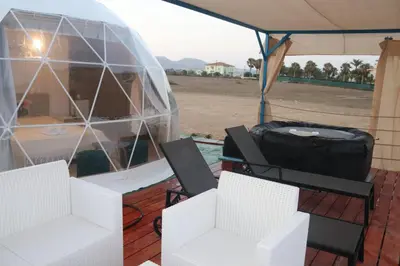 a gazebo with two chairs and a table and a boat at Domes at the Beach in Maroni