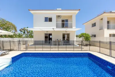 a villa with a swimming pool in front of a house at Villa Chrystalla in Paralimni