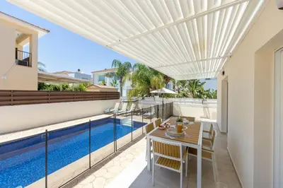 a patio with a table and chairs and a swimming pool at Villa Chrystalla in Paralimni