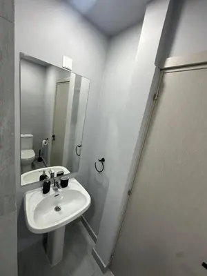 a white bathroom with a sink and a mirror at Finikoudes Central Apartment in Larnaka