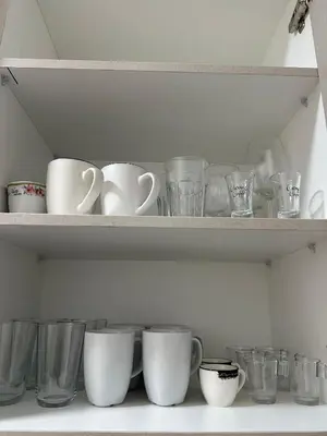 a shelf filled with cups and other glass items at Finikoudes Central Apartment in Larnaka