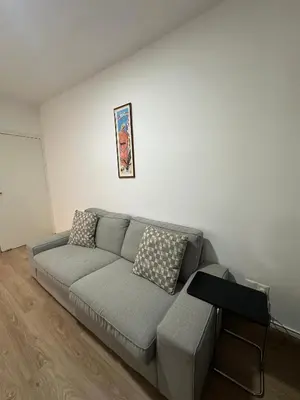 a living room with a gray couch and a table at Finikoudes Central Apartment in Larnaka