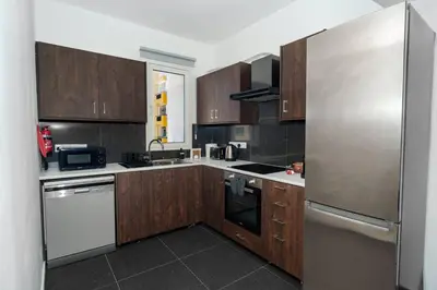 a kitchen with wooden cabinets and a stainless steel refrigerator at Central 2 bdr Flat St Lazaros - Phoenix Lodge in Larnaka