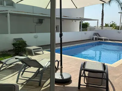 two views of a swimming pool with an umbrella and chairs at TooCoool Villa - Elite Sea Breeze in Ayia Napa