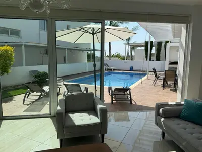 a living room with a pool and chairs and an umbrella at TooCoool Villa - Elite Sea Breeze in Ayia Napa