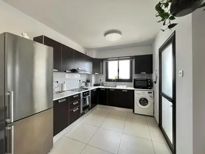 a kitchen with black cabinets and a stainless steel refrigerator at STAY Sealine Apartment in Larnaka