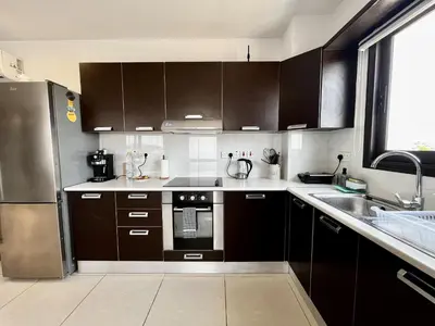 a kitchen with brown cabinets and a stainless steel refrigerator at STAY Sealine Apartment in Larnaka