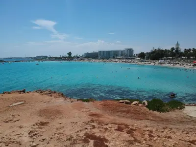 a beach with people swimming in the blue water at Nissi Cove 2 Bedroom Apartment in Ayia Napa