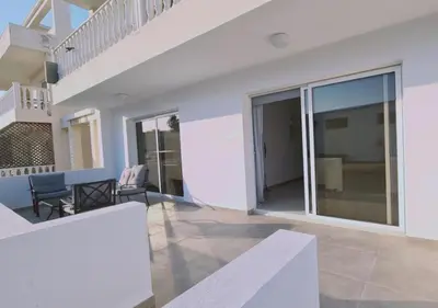 a white house with a staircase and a living room at Nissi Cove 2 Bedroom Apartment in Ayia Napa
