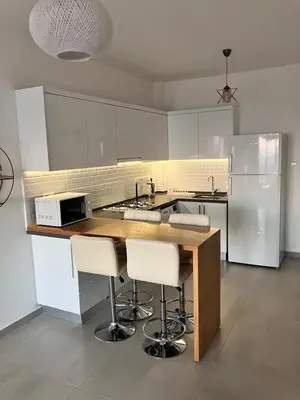 a kitchen with white cabinets and a counter with stools at Caesar Socrates Apartment in Larnaka