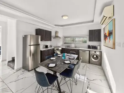 a kitchen with a table and chairs and a refrigerator at Alassia Blue Villa in Protaras