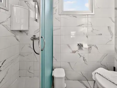 a bathroom with a shower with a toilet and a window at Alassia Blue Villa in Protaras