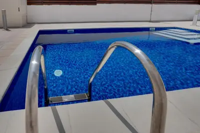 a swimming pool with blue water and metal rails at Amelia Beach Villa wpool -500mfrombeach in Voroklini
