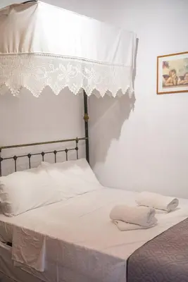 a white bed with two pillows on top of it at Maison Des Vignes Lofou in Lofou