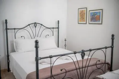 a bedroom with a black bed with a white bedspread at Maison Des Vignes Lofou in Lofou