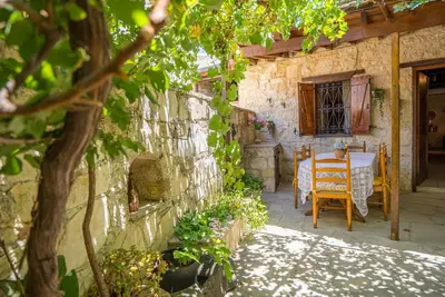 a stone house with a table and chairs in a yard at Maison Des Vignes Lofou in Lofou
