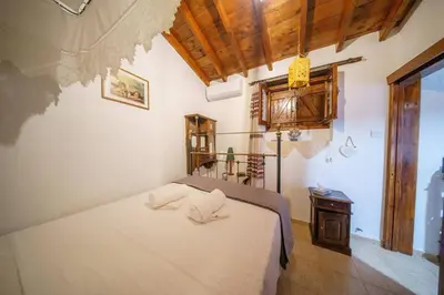 a bedroom with a white bed and a table at Maison Des Vignes Lofou in Lofou