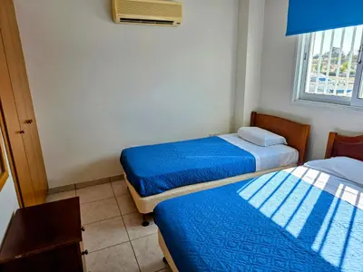 two beds in a small room with blue sheets at Niki's Coastal Escape in Larnaka