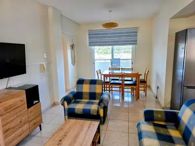 a living room with a table and chairs and a television at Niki's Coastal Escape in Larnaka