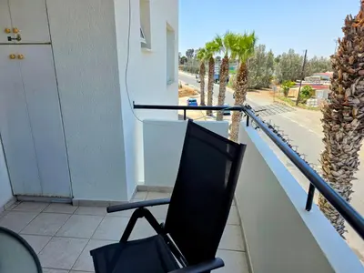 a chair on a balcony with a view of a street at Niki's Coastal Escape in Larnaka