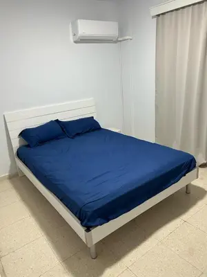 a bed with blue sheets and a white headboard at The relaxing apartment in Paralimni