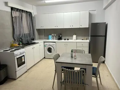 a kitchen with white cabinets and a table with chairs at The relaxing apartment in Paralimni