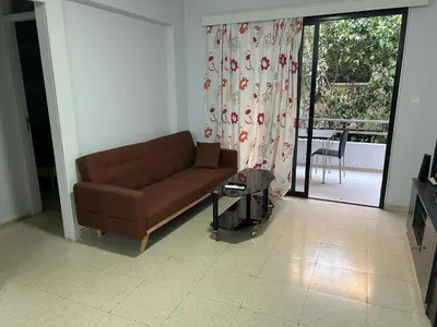 a living room with a brown couch and a sliding glass door at The relaxing apartment in Paralimni