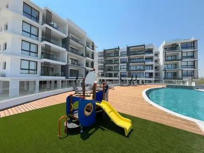an apartment with a playground next to a swimming pool at Larnaca Elysium Seaside & Pool Retreat in Livadhia
