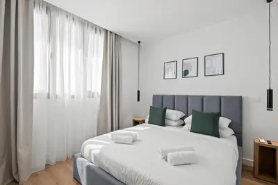 a white bedroom with a large bed with green pillows at Artemis 204 - Seaside Stories in Livadhia