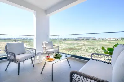 a living room with chairs and a table and large windows at Artemis 204 - Seaside Stories in Livadhia