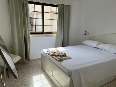 a white bedroom with a bed and a window at Nice Room in Limassol center in Limassol