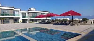 a swimming pool with umbrellas and chairs and a building at Sunprime Premium Site in Pyla