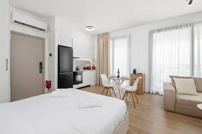 a white bedroom with a bed and a couch and a table at Artemis 102 - Seaside Stories in Livadhia