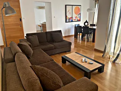 a living room with a brown couch and a table at Charm Flat in the heart of the City Center - Balcony & view in Nicosia