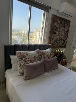 a bed with pillows in a room with large windows at Atalanta rooms in Larnaka