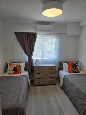 a bedroom with two beds and a window at Protaras Ayios Elias Maisonette in Protaras